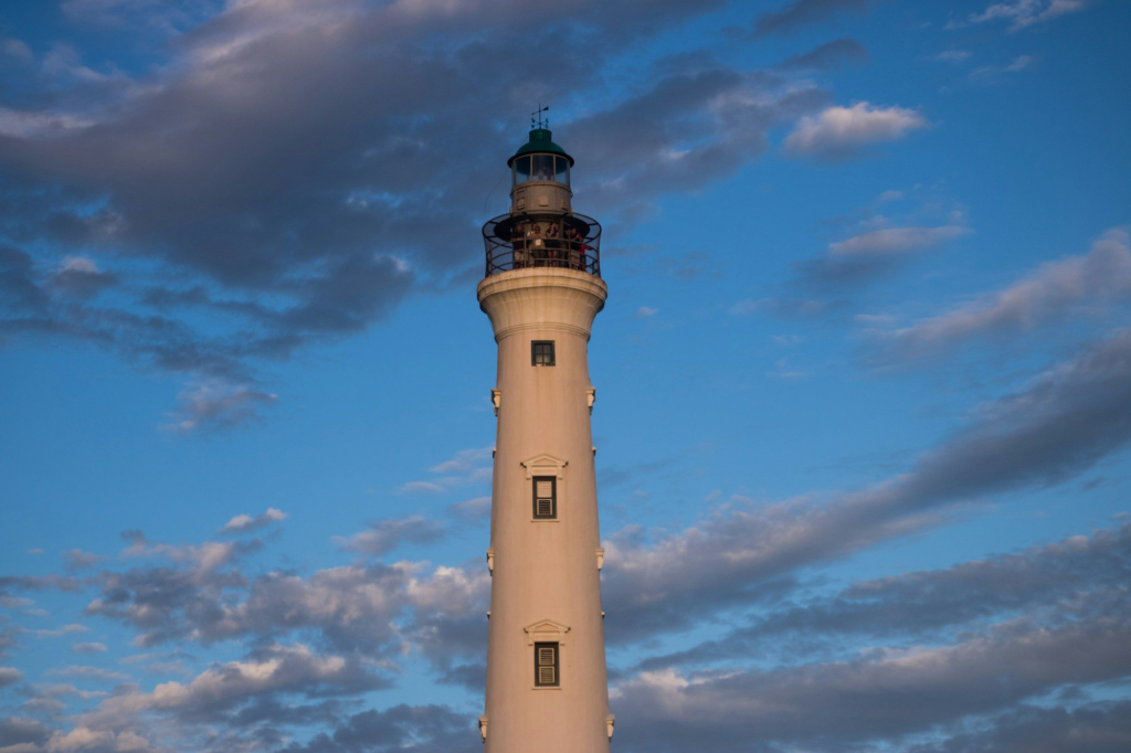 A lighthouse in Aruba under a cloudy blue sky