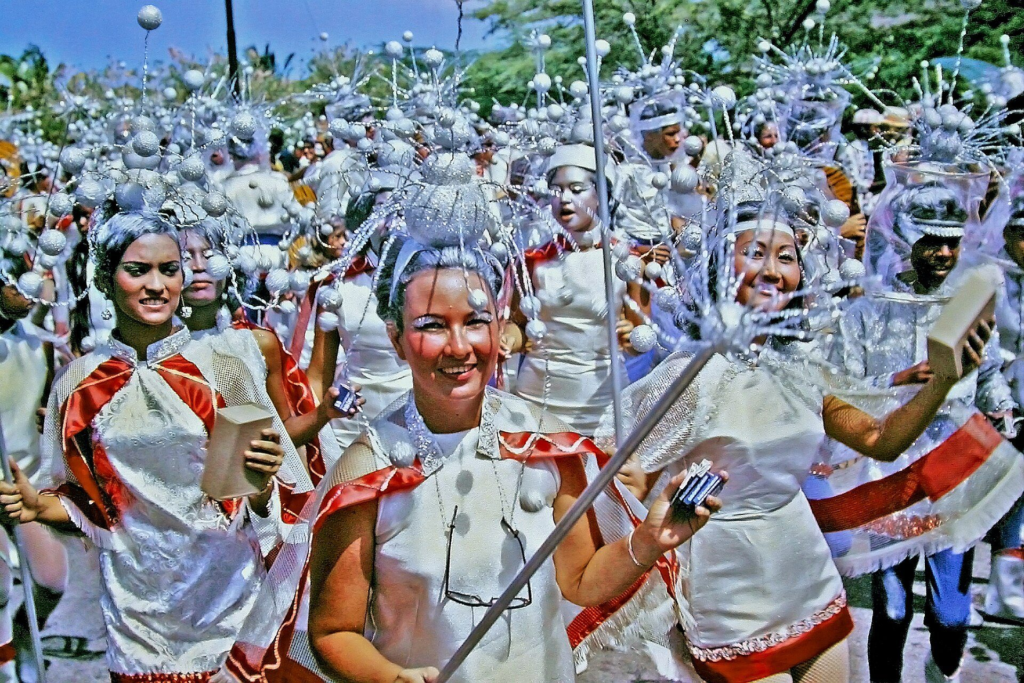 A Carnival group in matching silver costumes dancing in a parade in Aruba, 1969