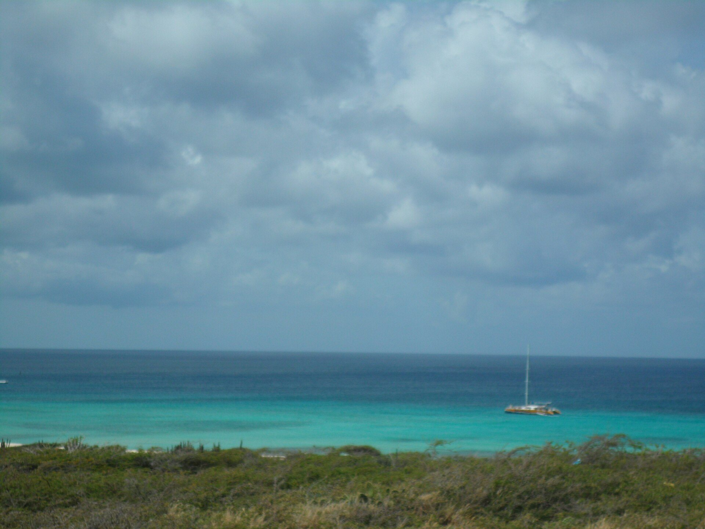 A catamaran at anchor in Arashi Bay, seen from the dunes