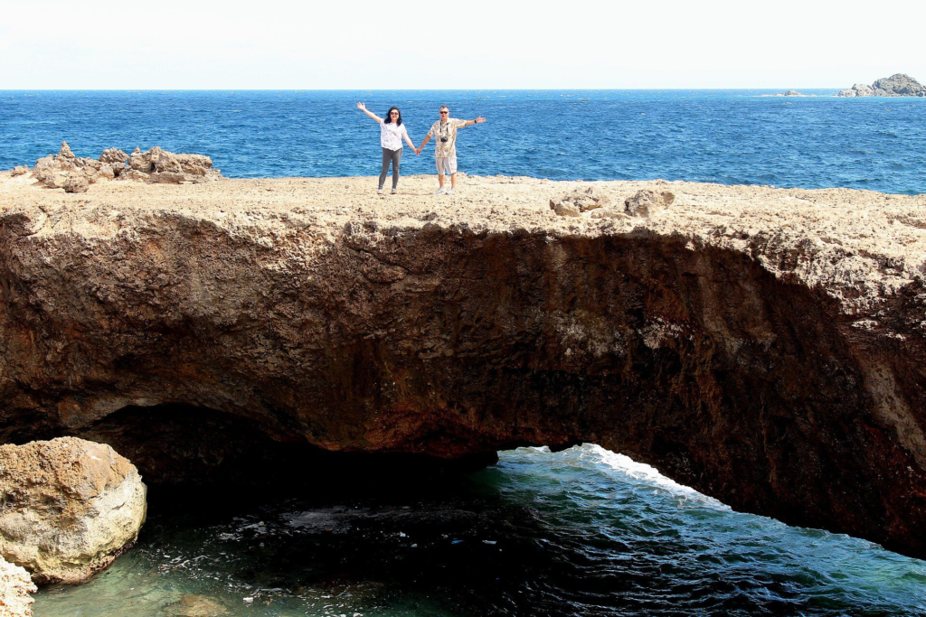 Visitors standing on a limestone natural bridge on Aruba's north coast