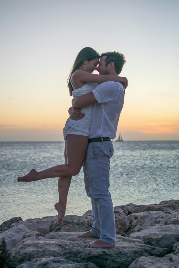 A couple standing on coastal rocks at sunset in Aruba