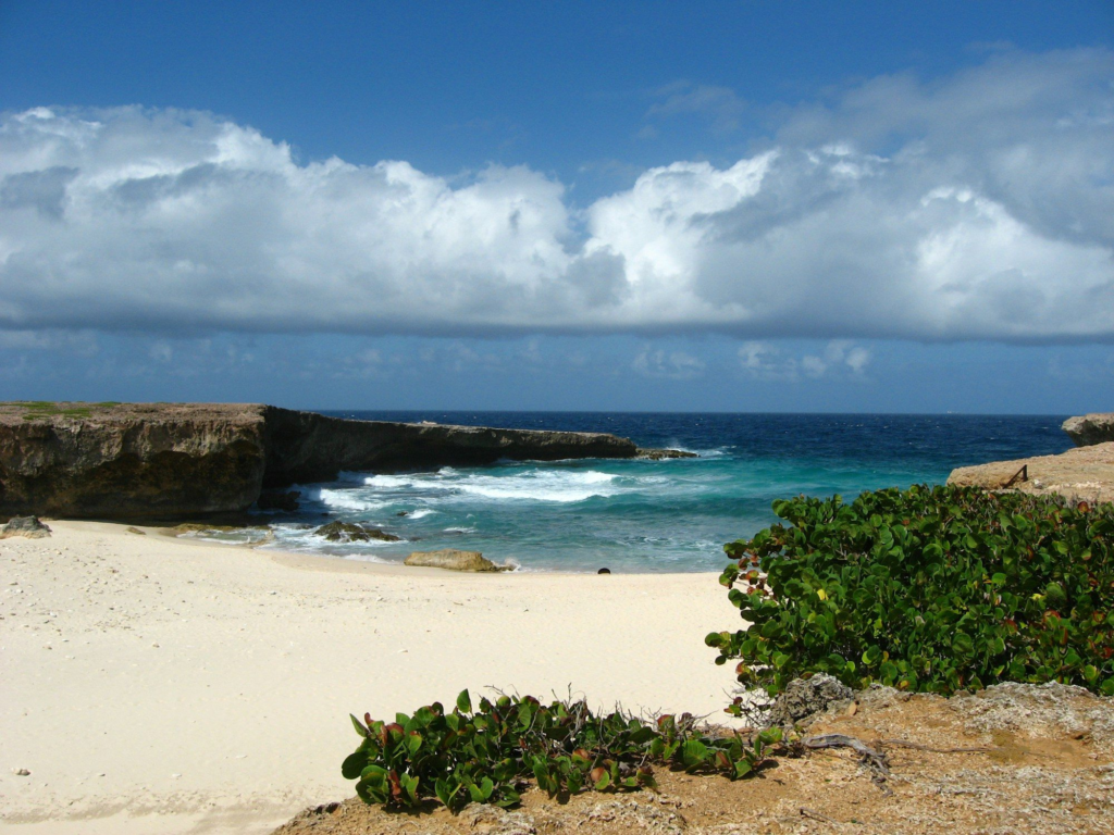 Clouds over a sandy beach and blue water in Aruba