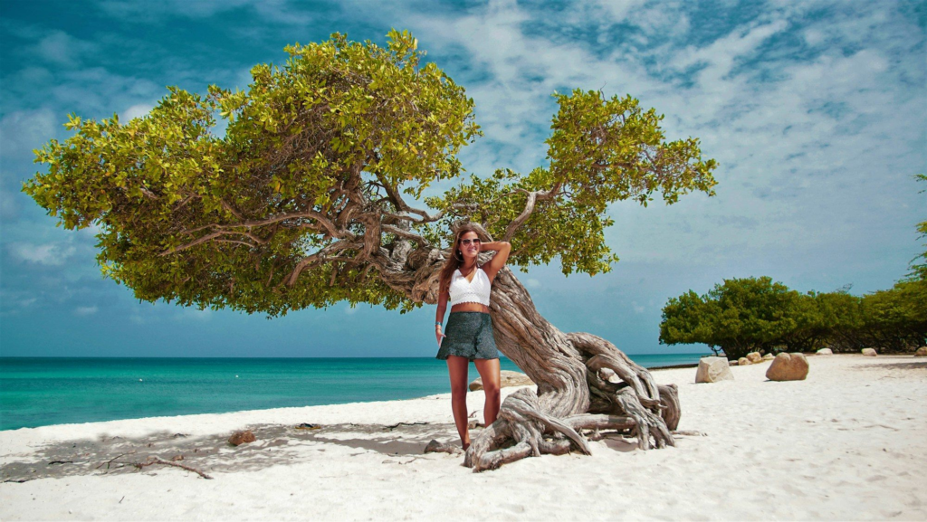Woman posing beside a tree on Eagle Beach