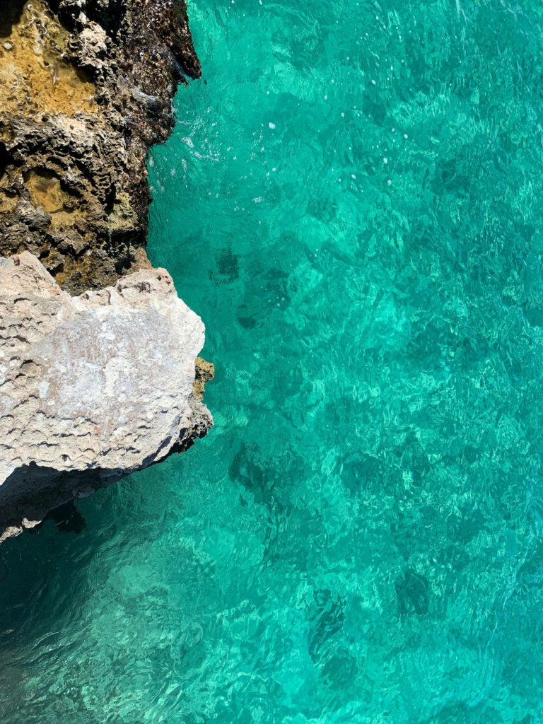 Clear turquoise water seen from a rocky cliff in Aruba