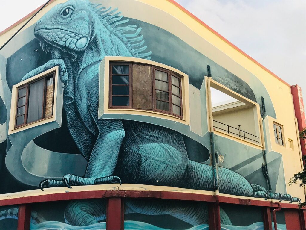A large iguana mural covering a corner building in San Nicolas, Aruba